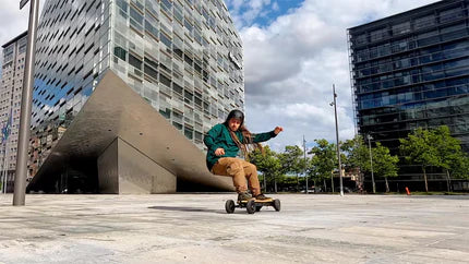 A person skateboarding in an urban environment with modern buildings in the background.