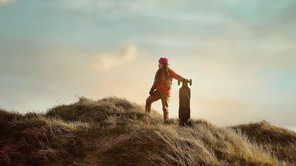 A woman standing on a hilltop with an electric skateboard