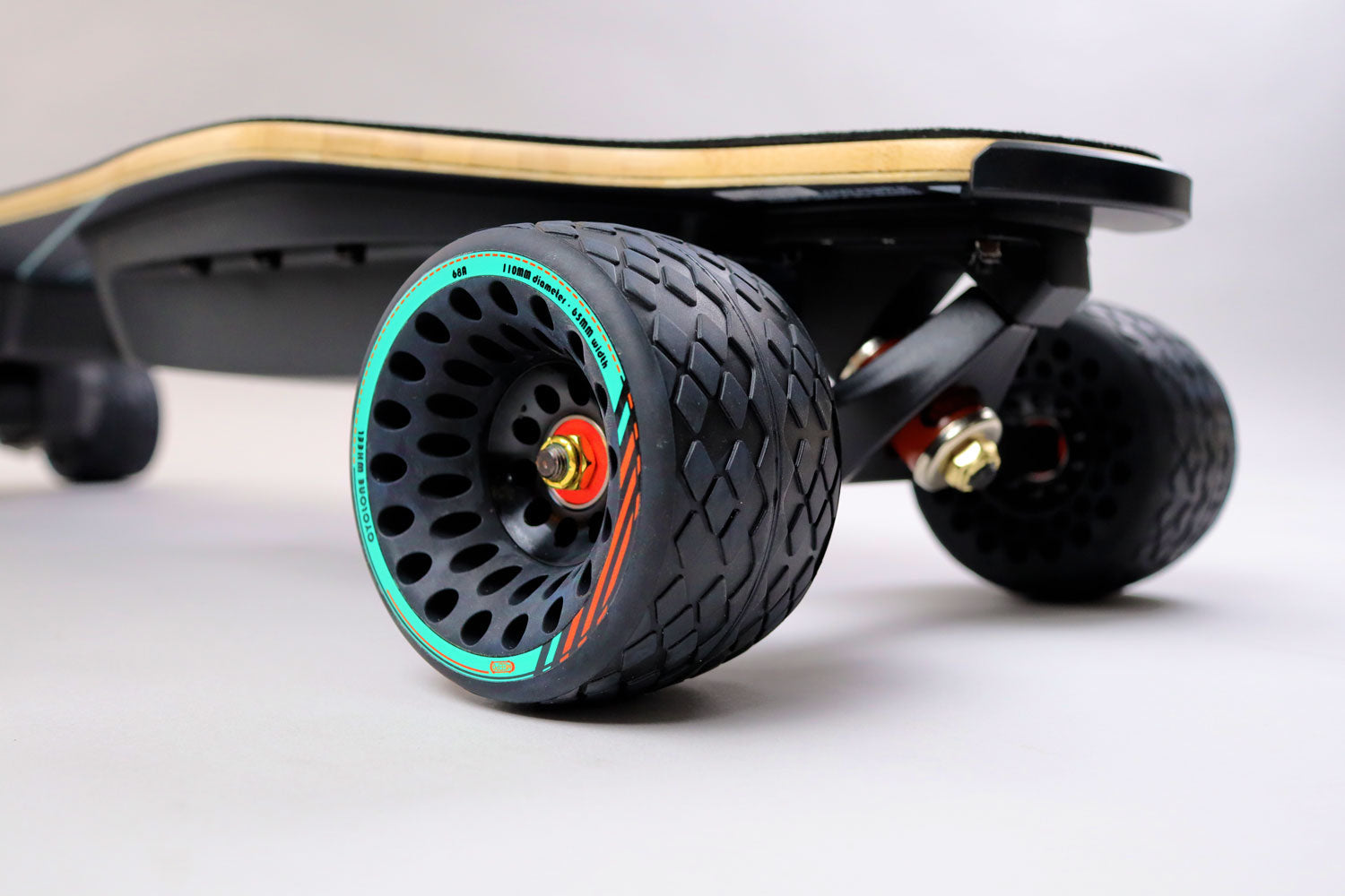  An electric skateboard with large, textured wheels and a teal-colored rim