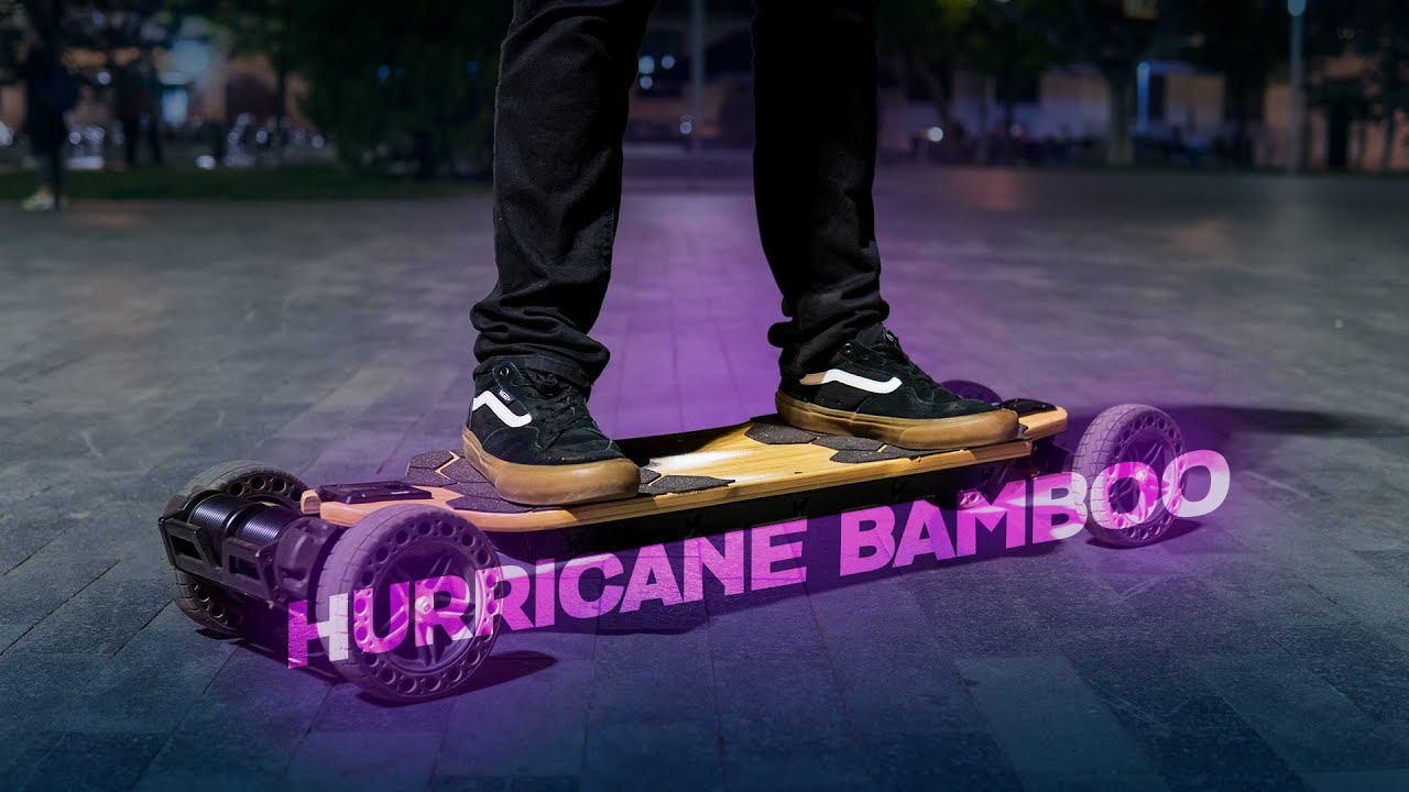 A person stands on an electric skateboard labeled "HURRICANE BAMBOO" at night.