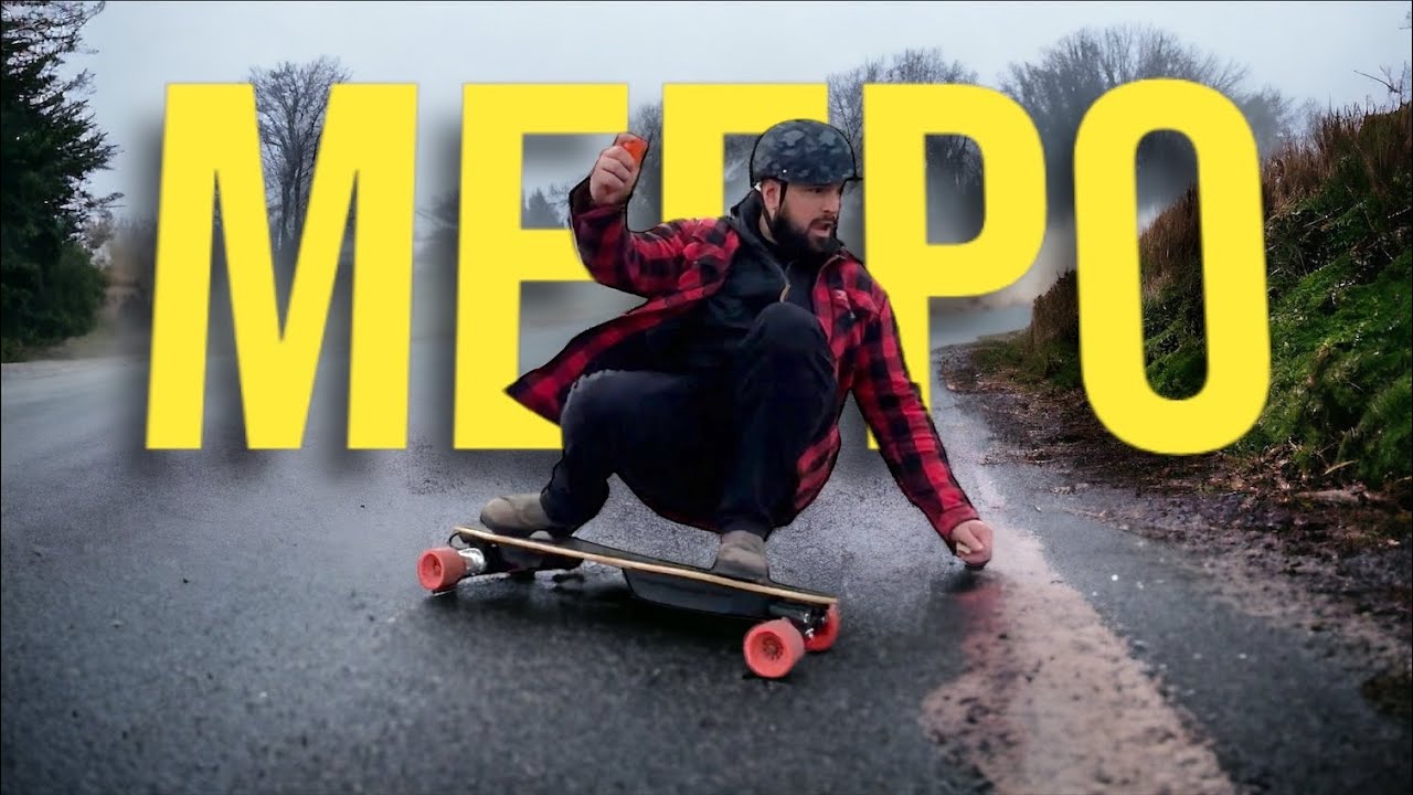 A man in a plaid jacket and helmet rides an electric skateboard on a wet road, with "MEEDO" text overlayed.