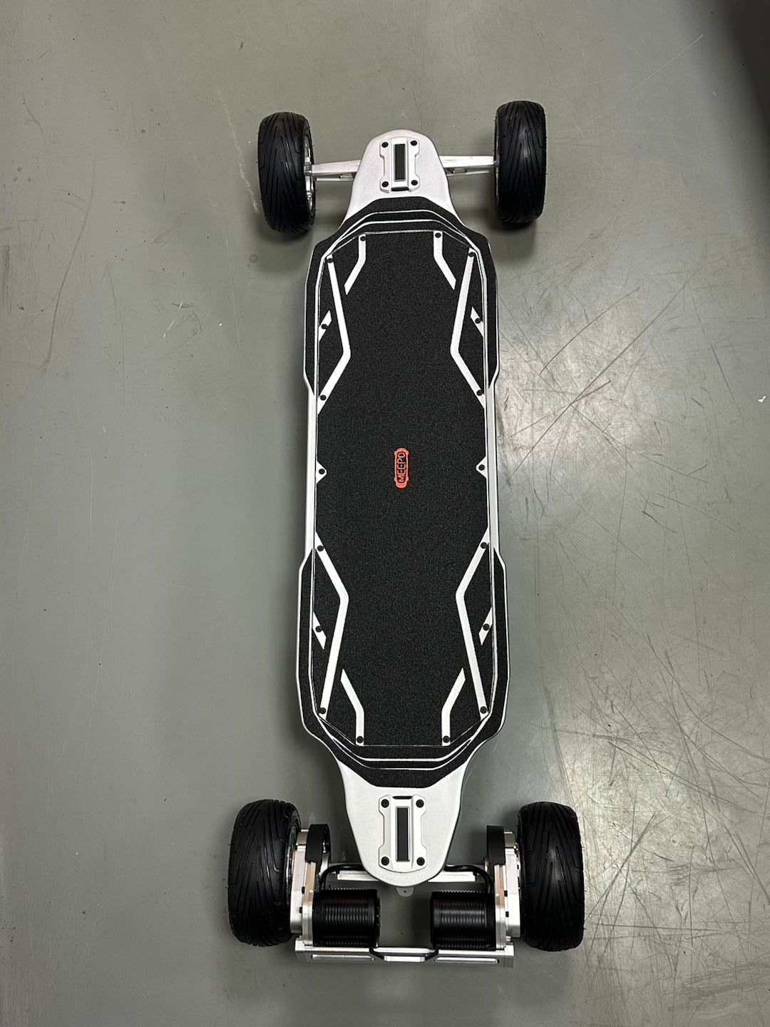 Top view of Meepo Hurricane Ultra X skateboard with black grip tape and rugged wheels.