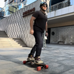 Man riding Meepo electric skateboard outside a sleek modern building